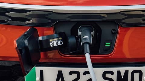 Orange Kia Niro charging, front end shot of port and cable