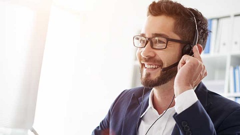 Young man with glasses and beard talking into a headset