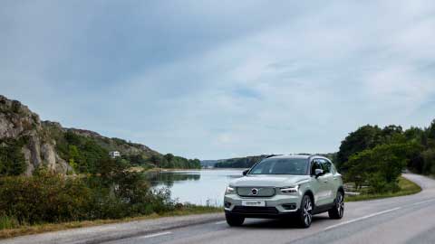 Silver Volvo XC60, driving down country road with lake in background