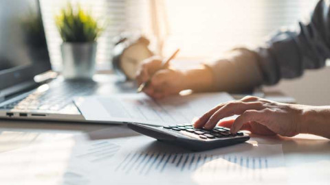Person On Laptop And Calculator