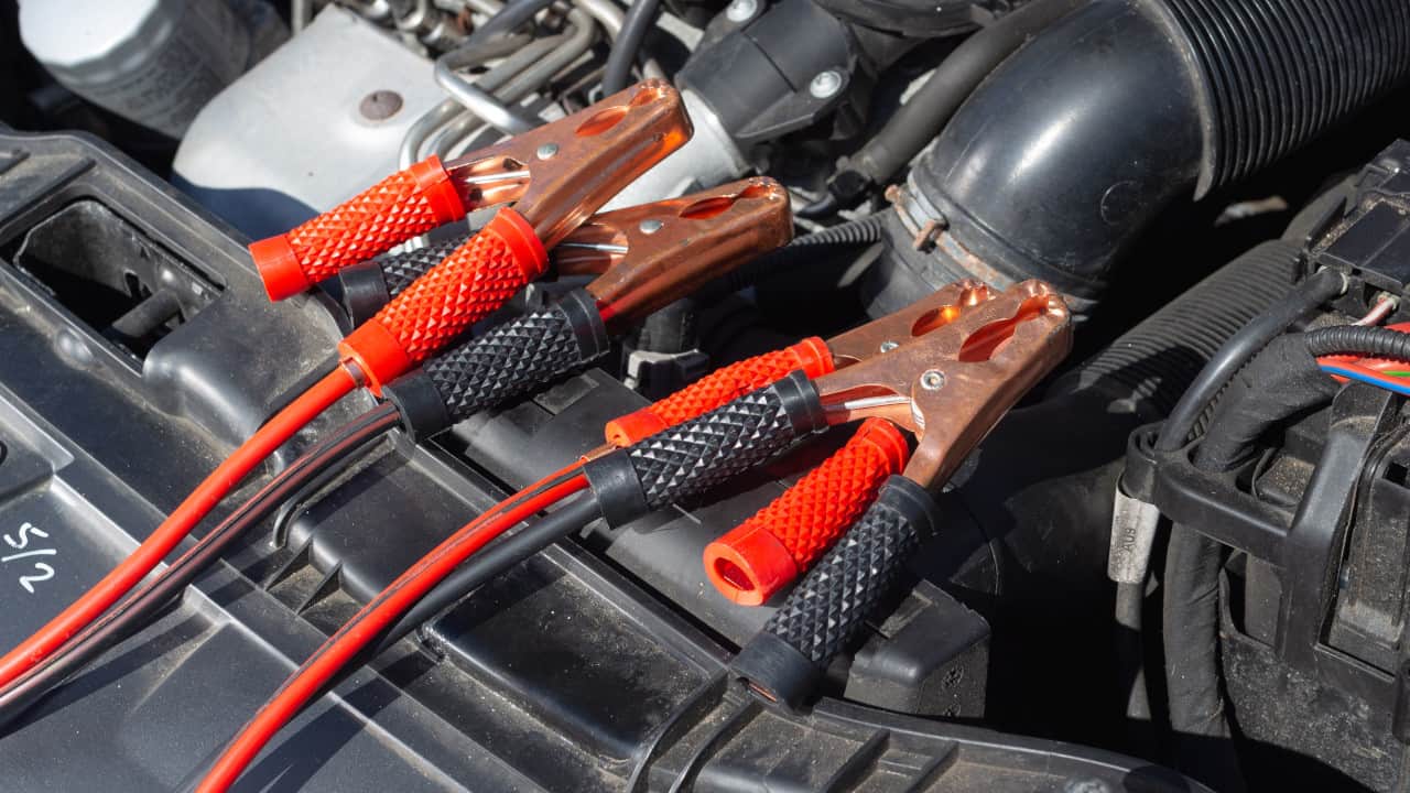 Pair of red jumper cables sitting on top of an engine bay
